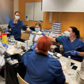 Seinäjoen terveyskeskuksen työntekijät annostelevat koronarokotteita valmiiksi annoksiksi rokotustapahtumassa.