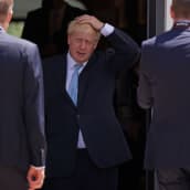 Boris Johnson astuu oviaukosta pidellen päätään.