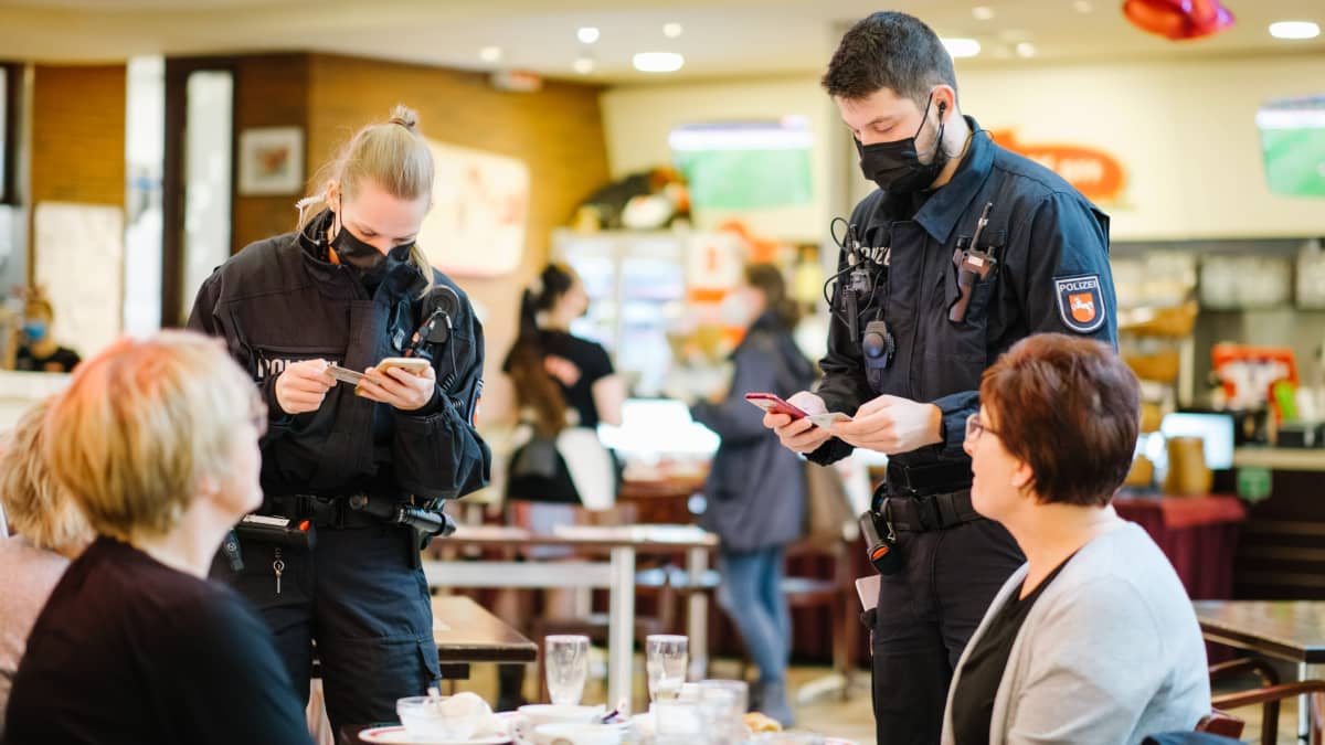 Poliisit tarkastavat koronapasseja ruokailijoilta ravintolassa.