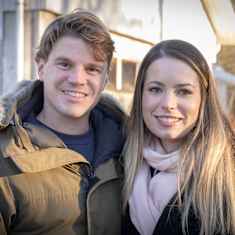 A couple stands in a wintry landscape. 
