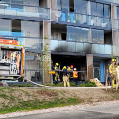 Kerrostaloasunto Espoon Kivenlahdessa syttyi tuleen. Kuvassa kerrostalon ulkosivu, vasemmalla paloauto ja oikealla ihmisiä. 