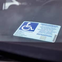 Vammaisen pysäköintilupa auton kojelaudalla.