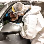 Koronatestin näytteenottajan ottaa testattavalta nenänäytettä drive-in testauspisteellä.