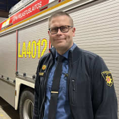 Pelastuslaitoksen siniseen takkiin pukeutunut pelastusjohtaja Markus Aarto  Lapin pelastuslaitokselta seisoo paloauton sivulla paloasemalla.