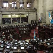 Guatemalan kongressin istuntosali. Presidentti puhuu puhujankorokkeella.