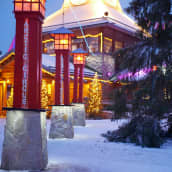 Jultomtens fabrik i Rovaniemi från utsidan i skymning upplyst av färgglada lampor