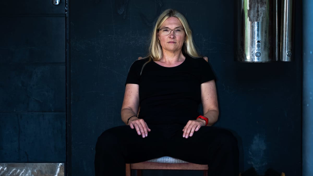 Kirsi Marie Liimatainen istuu ulos jätetyllä keittiöntuolilla kerrostalon edustalla.