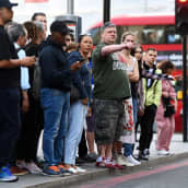 Ihmiset jonottavat bussipysäkillä.