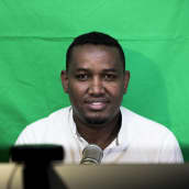 Hassan Halanen juontamassa podcast lähetystä omassa olohuoneessaan.