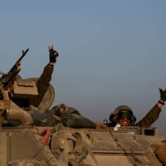 Israelin sotilaat tuulettavat ja näyttävät voiton merkkiä tankin katolla tulitauon alettua Gazassa.
