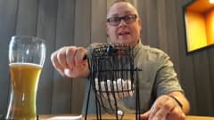 Mies pyörittää kammestaa pientä bingokonetta.
