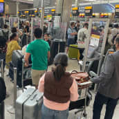 Resenärer med bagage köar på Heathrow flygplats.