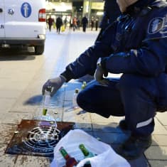  Poliisi kaataa nuorilta takavarikoituja alkoholijuomia viemäriin Narinkkatorilla Helsingissä.