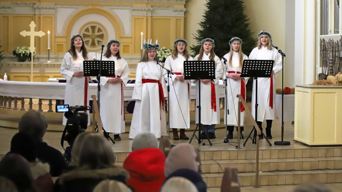 Mikkelin lukion Lucia-juhla Mikkelin tuomiokirkossa joulukuussa 2021, Lucia-kuoro laulaa yleisön edessä.