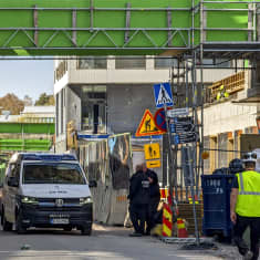 Poliisiauto tiellä, jonka yli kulkee tilapäinen kävelysilta, josta puuttuu lattia.