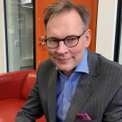 Riihimäen Tilat ja Kehitys Oy:n toimitusjohtaja Mika Herpiö istuu punaisella nahkasohvalla puolilähikuvassa, taustalla toimistotilaa.