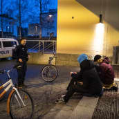 Poliisi jututtaa nuorisoa Kajaanissa syysiltana. Nuoret istuvat portailla. 