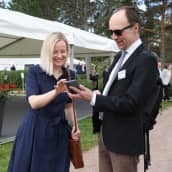 Riikka Purra ja Jussi Halla-aho Kultarannassa seisovat vierekkäin ja katsovat puhelinta.