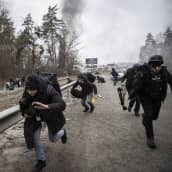 Ukrainalaisia ja median edustajia juoksee pois Venäjän tulituksen alta Irpinissä. lähellä Ukraina pääkaupunkia Kiovaa 6. maaliskuuta.