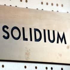 Metallilaatta, jossa on kaiverruksena Solidiumin logo ja Solidium-teksti.