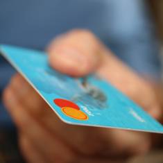 Photo shows a person holding a credit card.