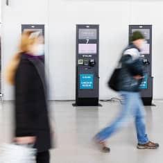 Lippuautomatteja Länsiterminaali 2:ssa, ohikulkevia ihmisä, ei tunnistettavia.