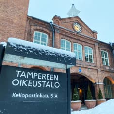 Luminen kyltti ”Tampereen oikeustalo” punatiilisen rakennuksen edustalla.
