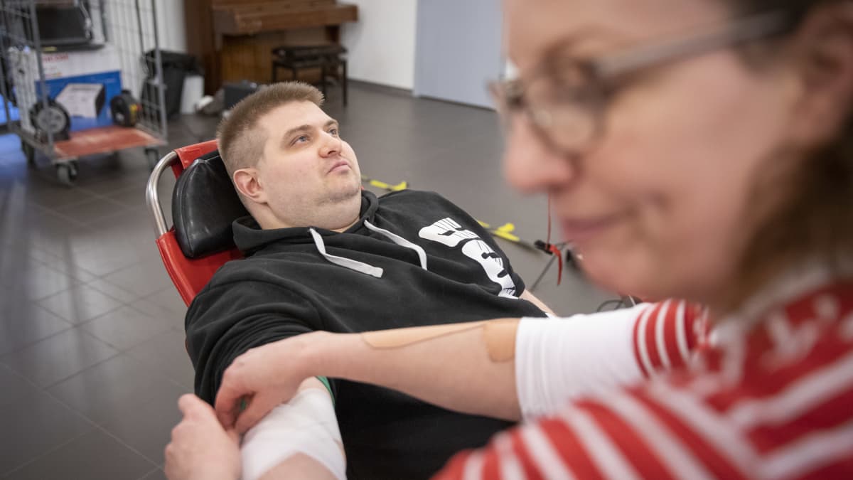 Sani Juselius laittaa sidettä juuri verta luovuttaneen Heikki Variksen käteen.