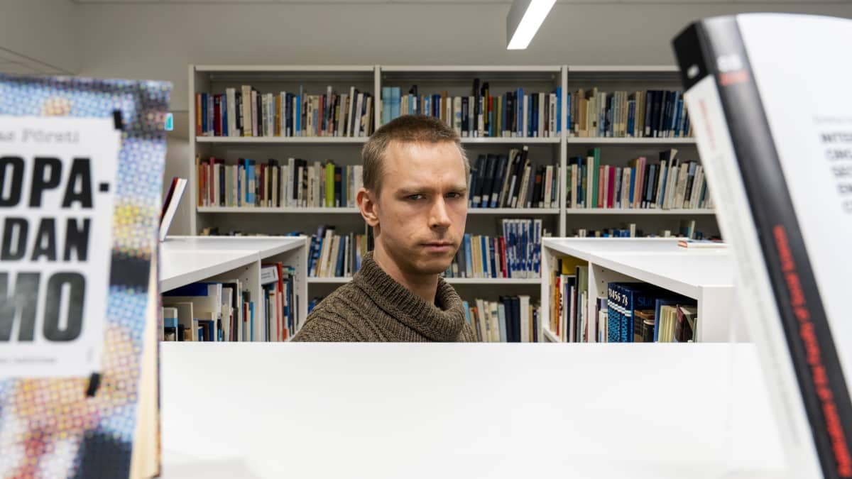 Jyri Lavikainen, Ulkopoliittisen instituutin tutkija seisoo kirjastossa ja katsoo kameraan.