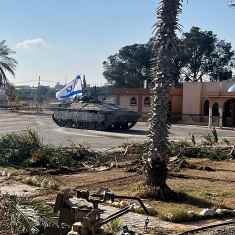 Israelin panssarivaunuja palmujen reunustamalla parkkipaikalla.