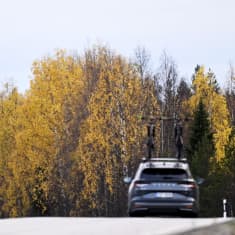 Auto ajaa ruskaisessa maisemassa kaksi pyörää kattotelineeseen kiinnitettynä.