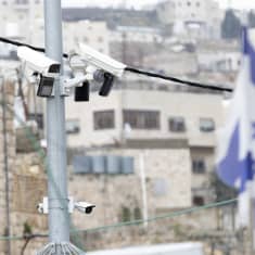 Useita valvontakameroita tolpassa, ja Israelin lippu taka-alalla.