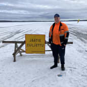 Viitasaarella Kymönkosken jäätietä ylläpitänyt Joni Nurmiranta jään sulusta kertovan kyltin vieressä.