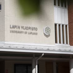 Vaaleassa laattaseinässä sisäänkäynnin yläpuolella Lapin Yliopiston logo ja teksti.