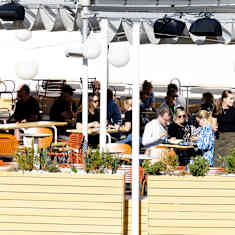 Photo shows people eating at a restaurant's terrace.