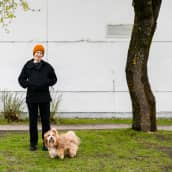 Nanne Pyrhönen ja Nova-koira poseeravat kameralle vaalean rakennuksen edessä.