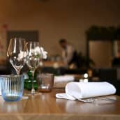 Ravintolan pöytä, taustalla näkyy ravintolan työntekijä epäselvänä hahmona.