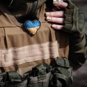 Sotilaan liivissä on kiinni punottu sydän Ukrainan väreissä.