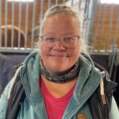 Outisen ratsastuskeskuksen yrittäjä Mia Lappalainen seisoo tallissa suomenhevosen edessä.