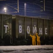 Kelta-asuiset ihmiset maalaavat junanvaunuun kyrillisiä kirjaimia