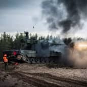 Heikkadyynin päällä olevan panssarivaunun tykistä tulee laukauksen johdosta tulta, runsaasti savua. 