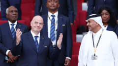 Gianni Infantino leveittää kätensä jalkapallostadionin katsomossa. Vierellään hänellä on Qatarin edustaja.