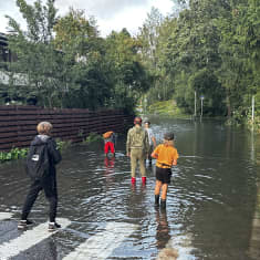 Barn vid översvämmad gång- och cykelväg vid bostadsområde. 