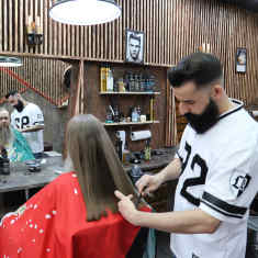 En man kipper en annan mans hår i en frisörsalong. 
