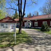 Riihimäen kaupunginmuseo ja sen pihaa sekä opastetaulu keväällä.