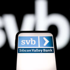 Matkapuhelimen näyttö, jossa lukee Silicon Valley Bank ja SVB. Myös mustalla taustalla näkyy SVB:n sinivalkoinen logo.