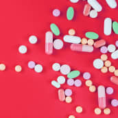Erilaisia pillereitä punaisella taustalla.
