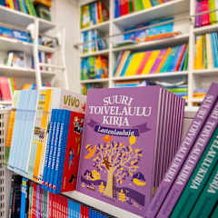 Kirjakaupan hyllyillä on värikkäitä kirjoja, kuten "Suuri Toivelaulukirja Lastenlauluja".