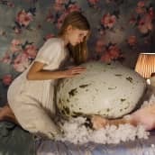 Tyttö istuu sängyllä ja tunnustelee edessään olevaa valtavan suurta linnunmunaa.