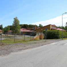 Skolområde i Kaskö med gula byggnader med röda tak. På gården syns klätterställingar och gungor.